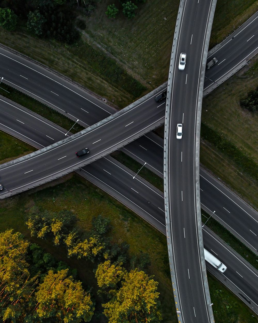 Aerial view of a multi-level highway interchange with cars crossing between green fields