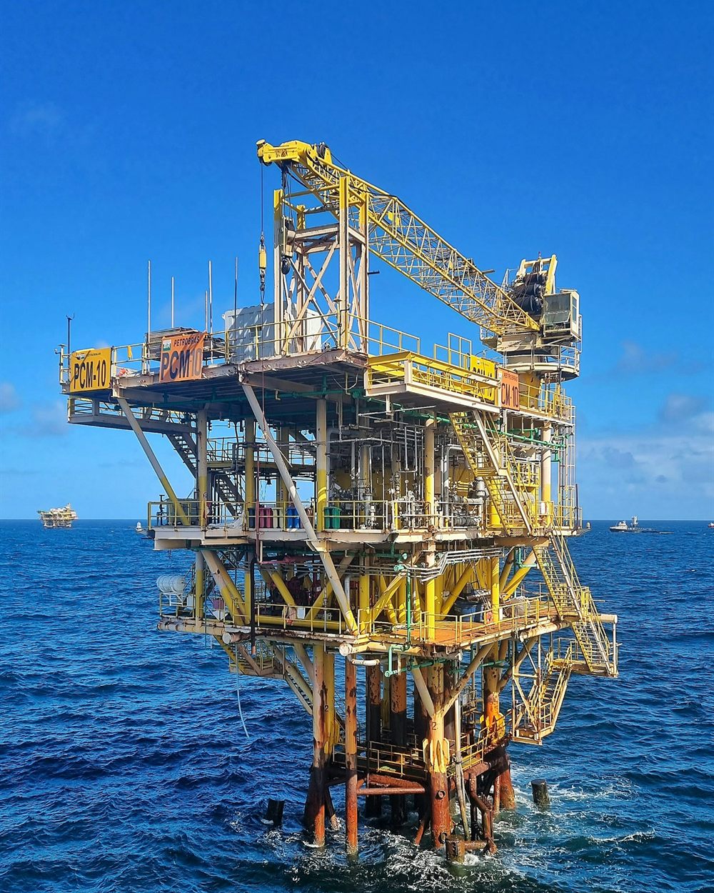 Offshore oil and gas production platform with a crane, standing in open blue sea