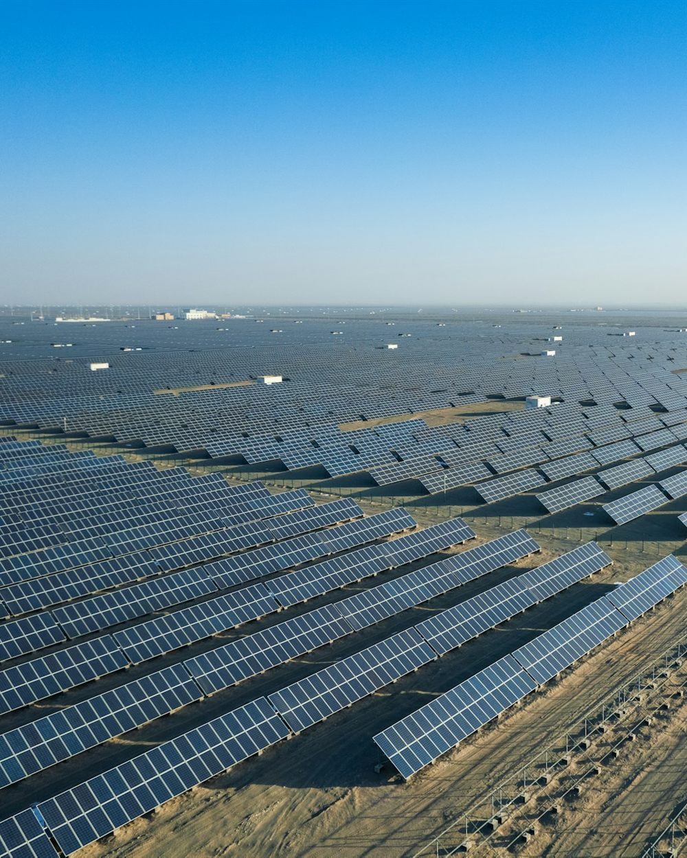 Aerial view of a vast solar power plant with rows of panels stretching to the horizon